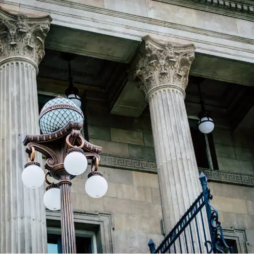 Ornate lamppost beside classical building columns.