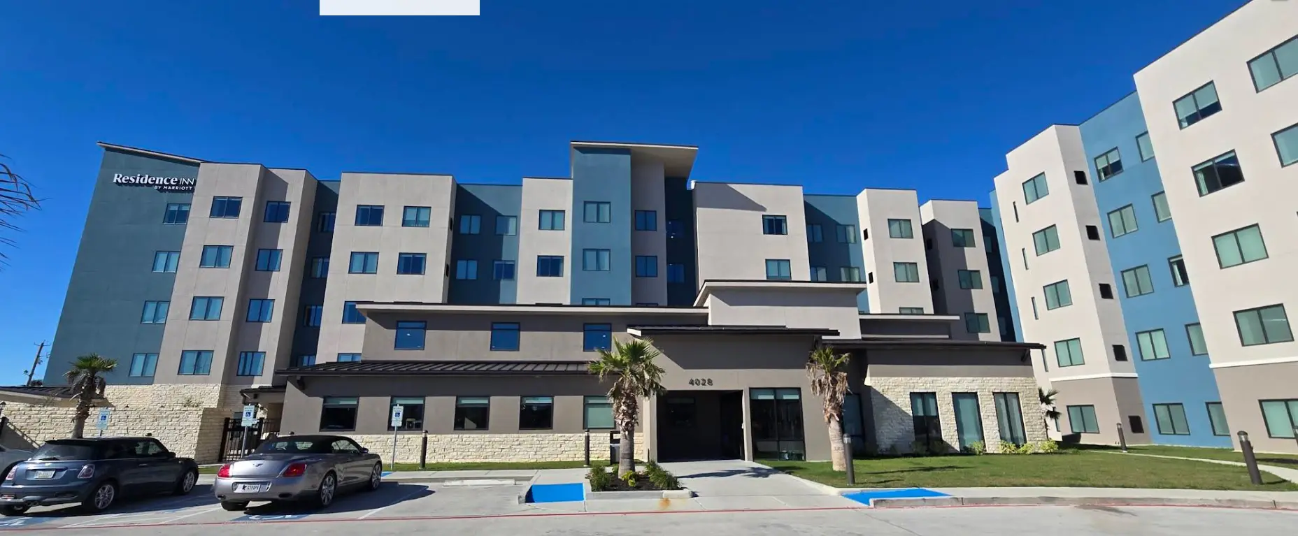 Modern mid-rise hotel façade with palm trees