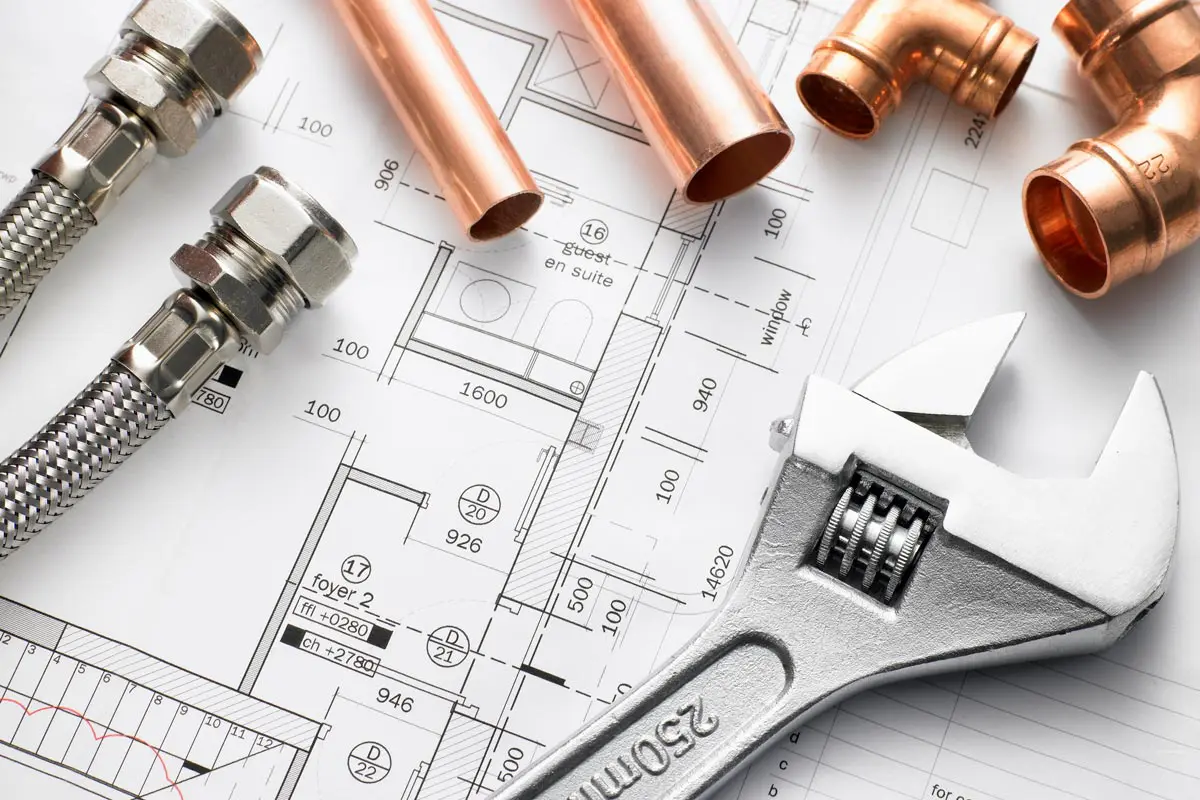Plumbing tools and copper pipes on blueprint